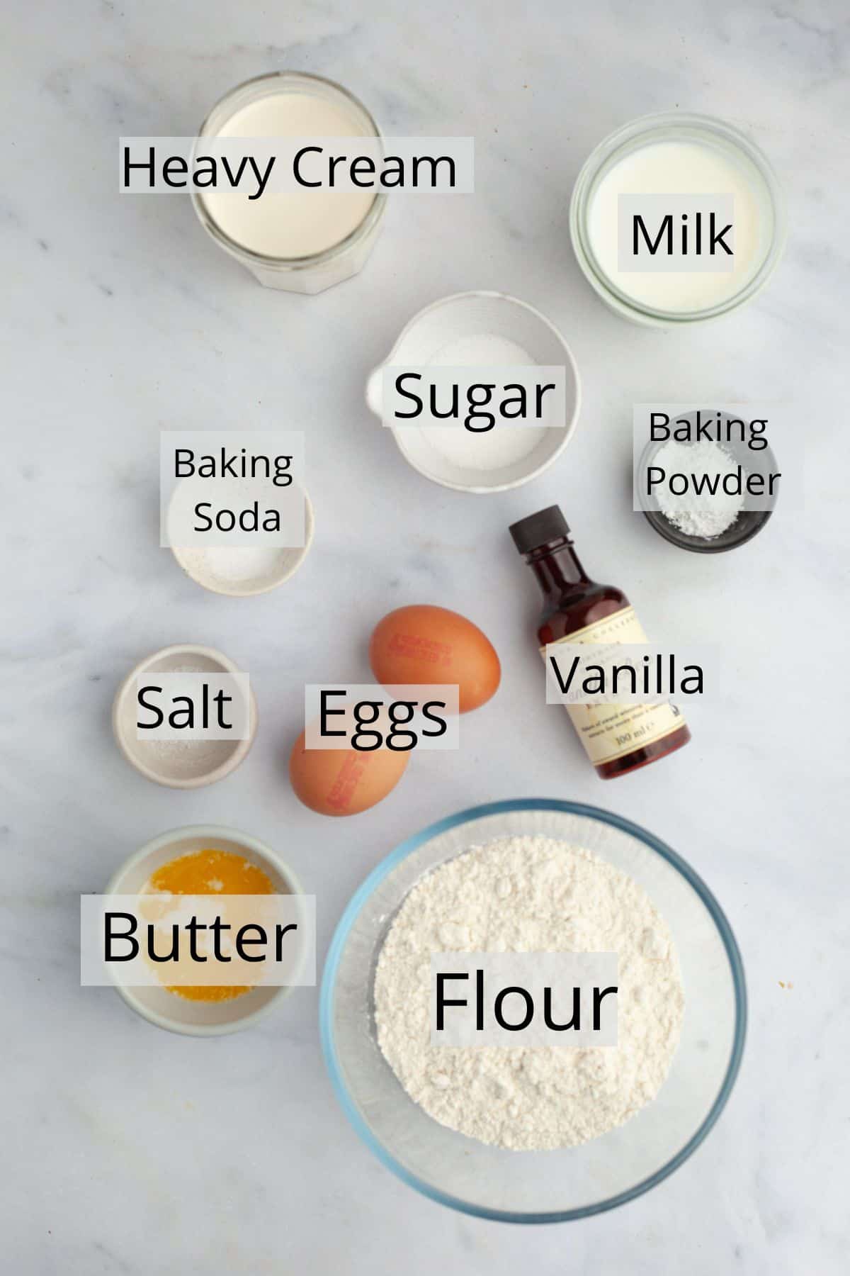 All the ingredients needed to make sweet cream pancakes, weighed out into small bowls.