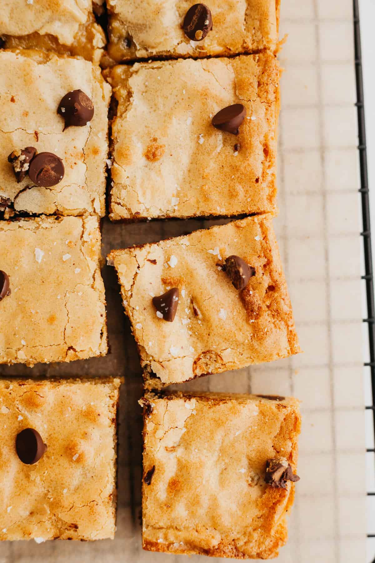 An overhead shot of sliced blondies with chocolate chips on parchment paper.