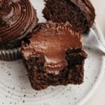 A chocolate cupcake sliced in half, showing a chocolate filling.