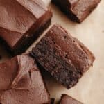 Brownies covered in chocolate cream cheese frosting on parchment paper.