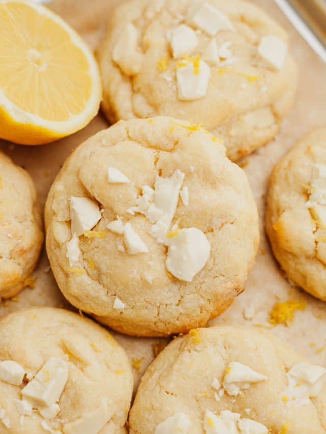 White chocolate lemon cookies on light brown parchment paper.