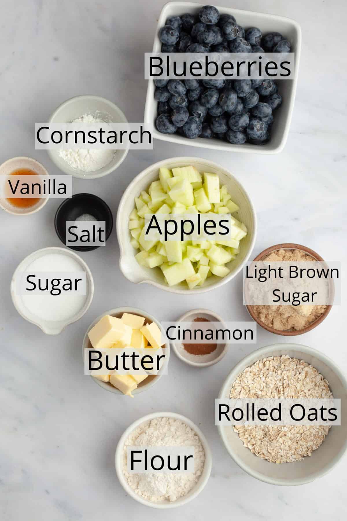 All the ingredients needed to make apple and blueberry crumble, weighed out into small bowls.
