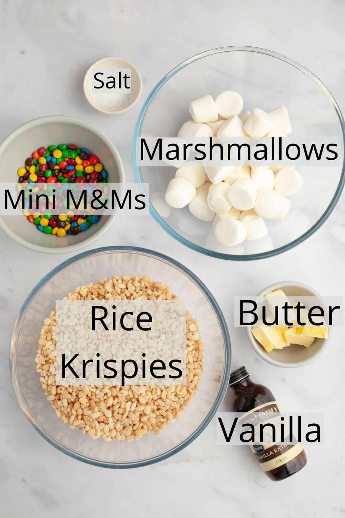 All the ingredients needed to make m&m rice krispie treats weighed out into small bowls.