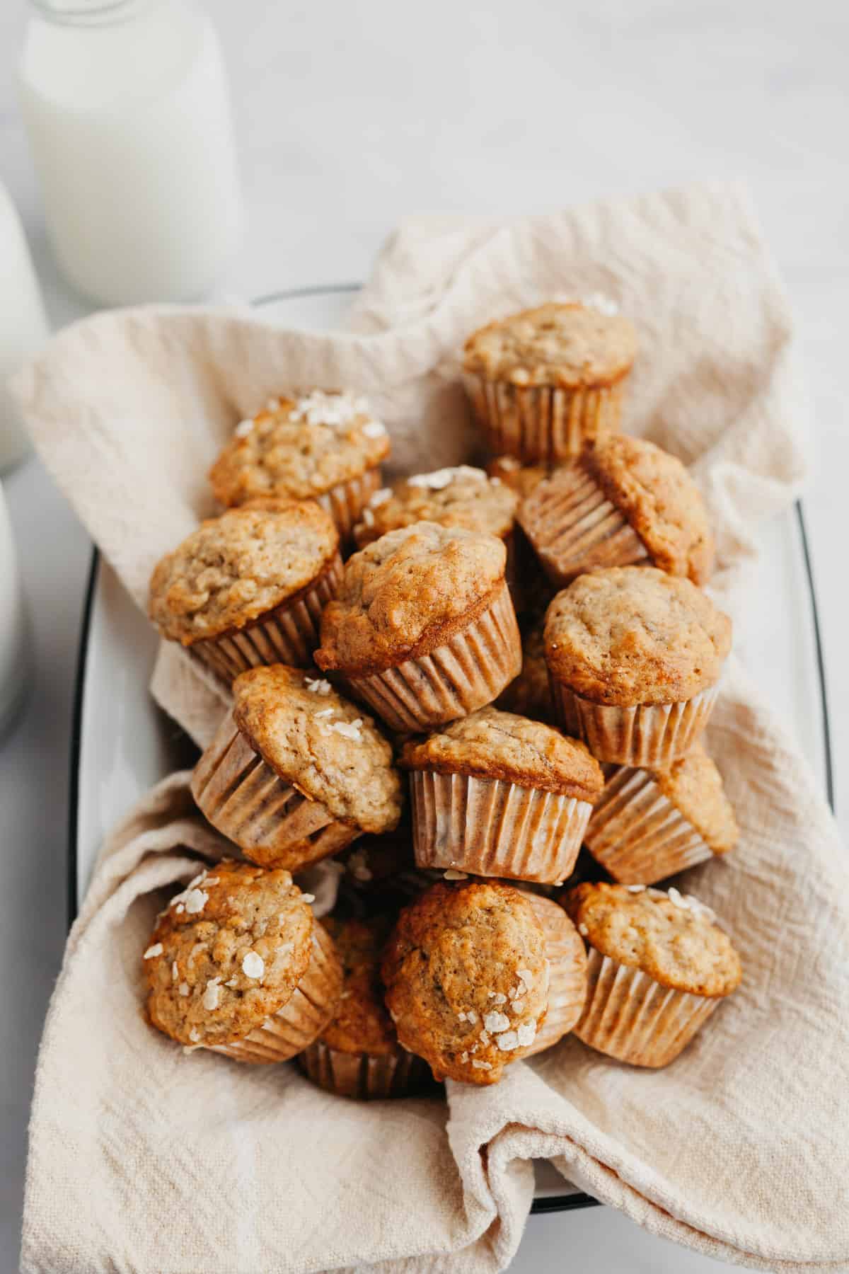A tin lined with a beige linen and filled with banana mini muffins.
