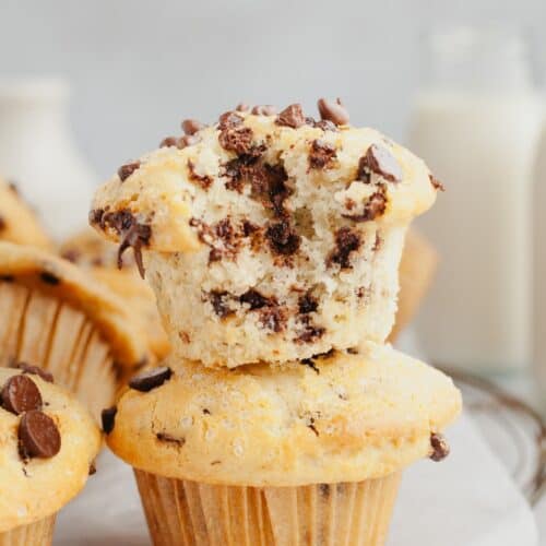 A chocolate chip muffin with a bite taken out of it on top of another muffin.