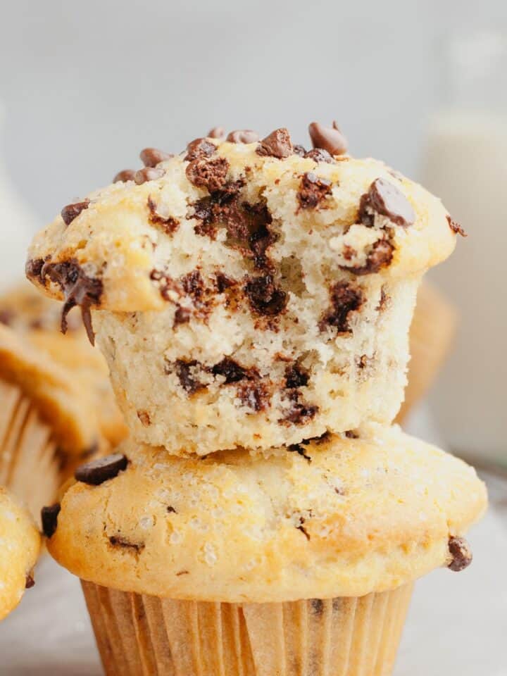 A chocolate chip muffin with a bite taken out of it on top of another muffin.