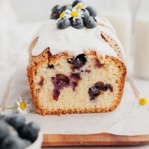 A blueberry loaf cake with a white glaze and blueberries on top.