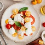 A burrata caprese salad on a small plate.