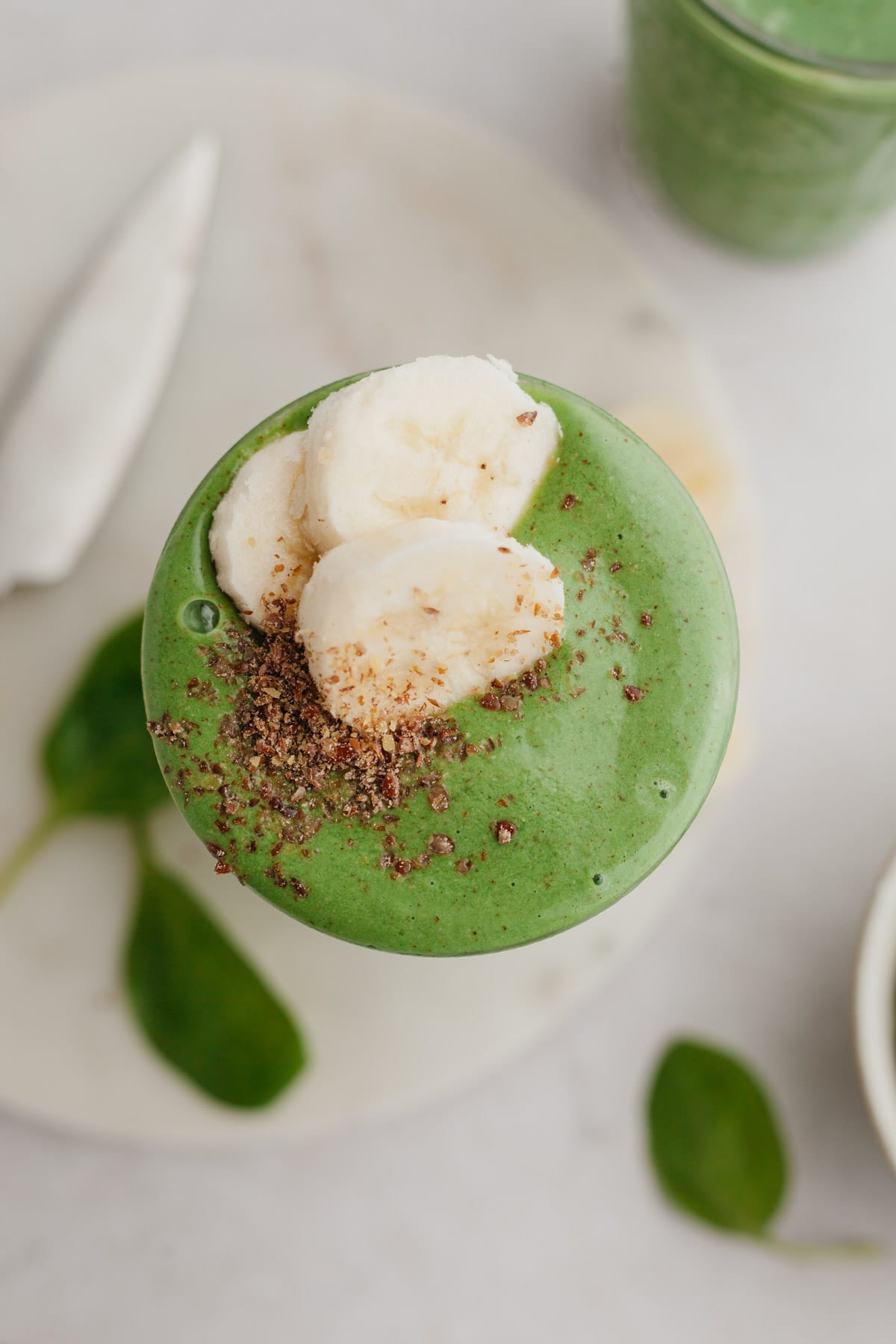 An overhead shot of spinach banana smoothie, it has several sliced bananas on top.