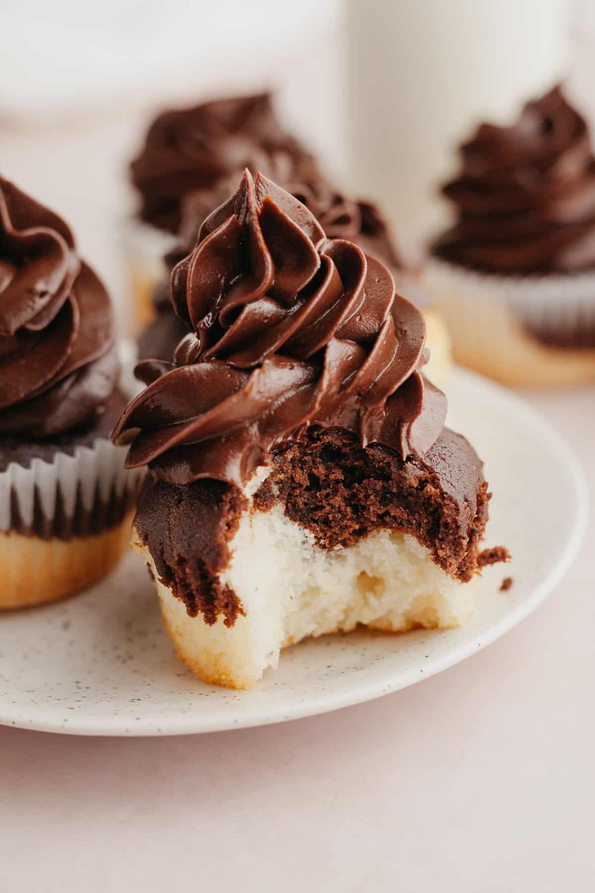 A close up of a marbled cupcake with chocolate frosting, a bite has been taken out of the cupcake.