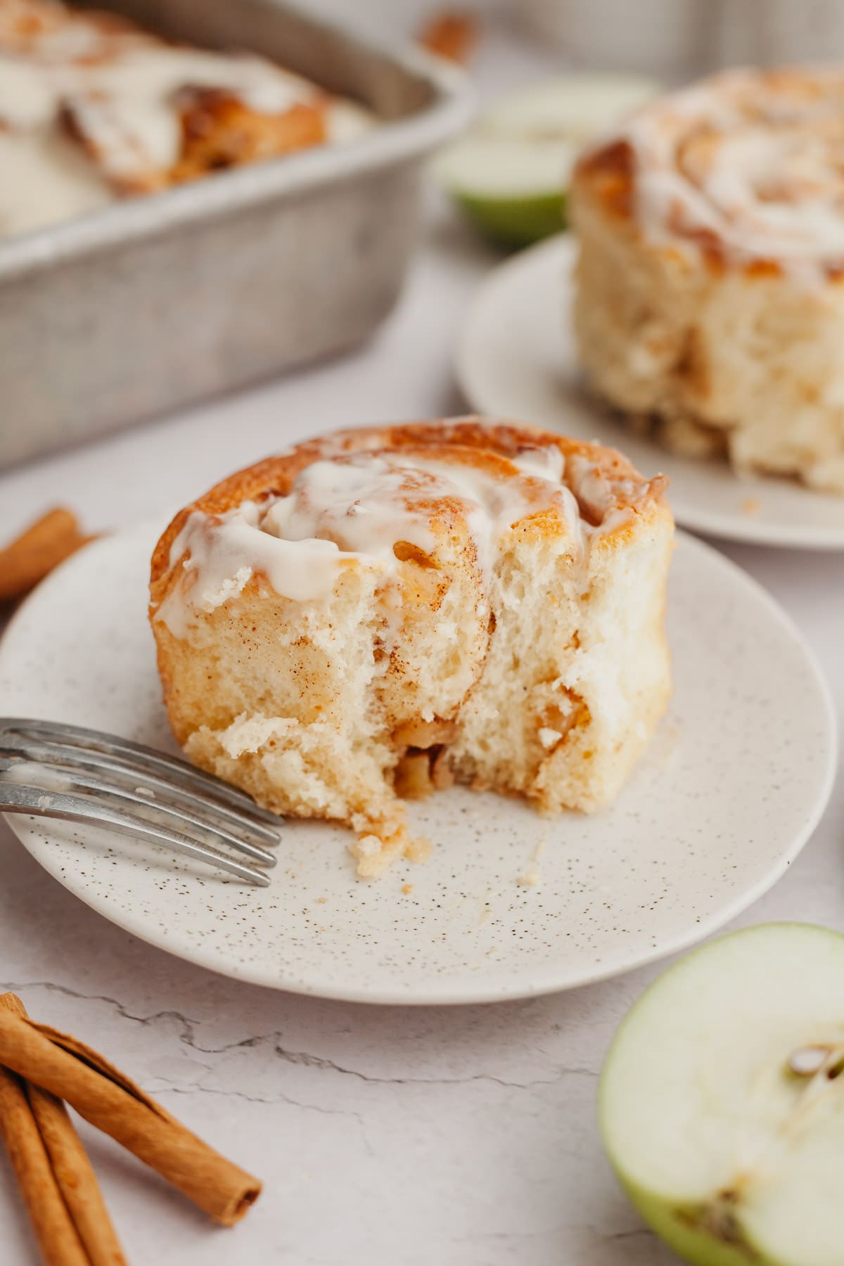 A cinnamon roll with apple pie filling on a small plate.