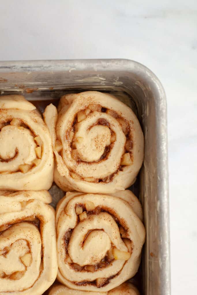 A close up of unbaked cinnamon rolls in a pan.