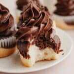 A close up of a marbled cupcake with chocolate frosting, a bite has been taken out of the cupcake.