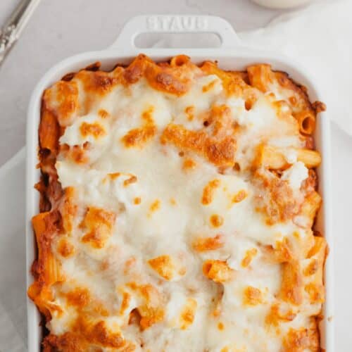 A white baking dish with a cheesy baked pasta in it.