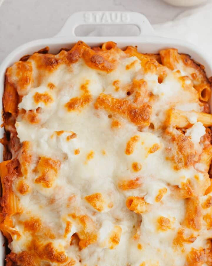 A white baking dish with a cheesy baked pasta in it.