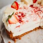 A slice of a strawberry white chocolate cheesecake on parchment paper.