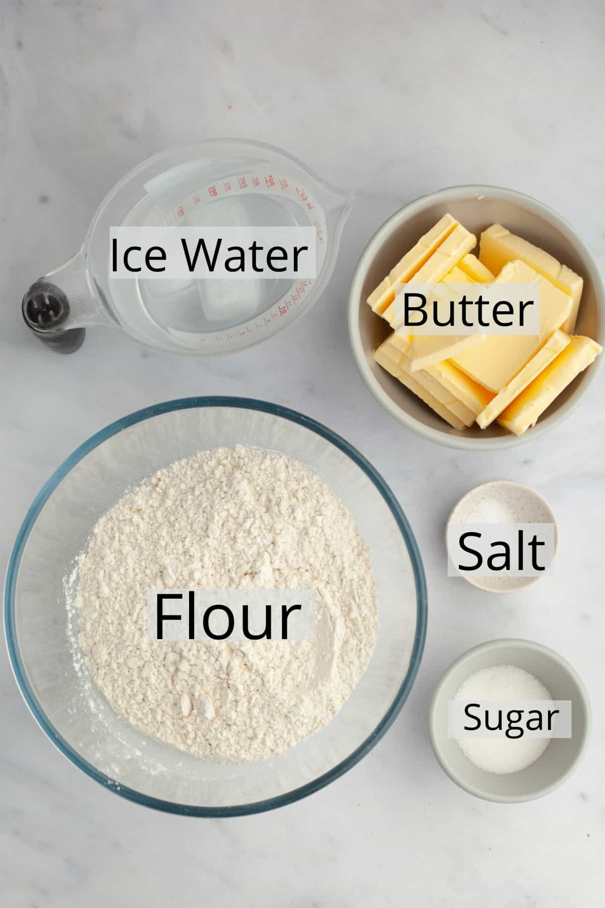 All the ingredients needed to make a pie crust weighed out into small bowls.