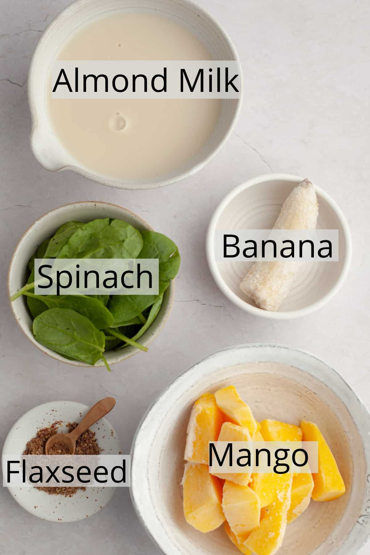 All the ingredients needed to make spinach mango smoothies, weighed out into small bowls.