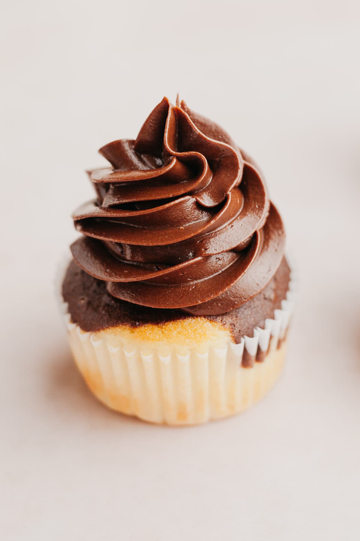 A close up of a cupcake with piped chocolate whipped ganache frosting.