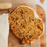 A slice of pumpkin bread on a wooden cutting board.