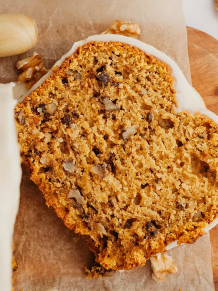 A slice of pumpkin bread on a wooden cutting board.