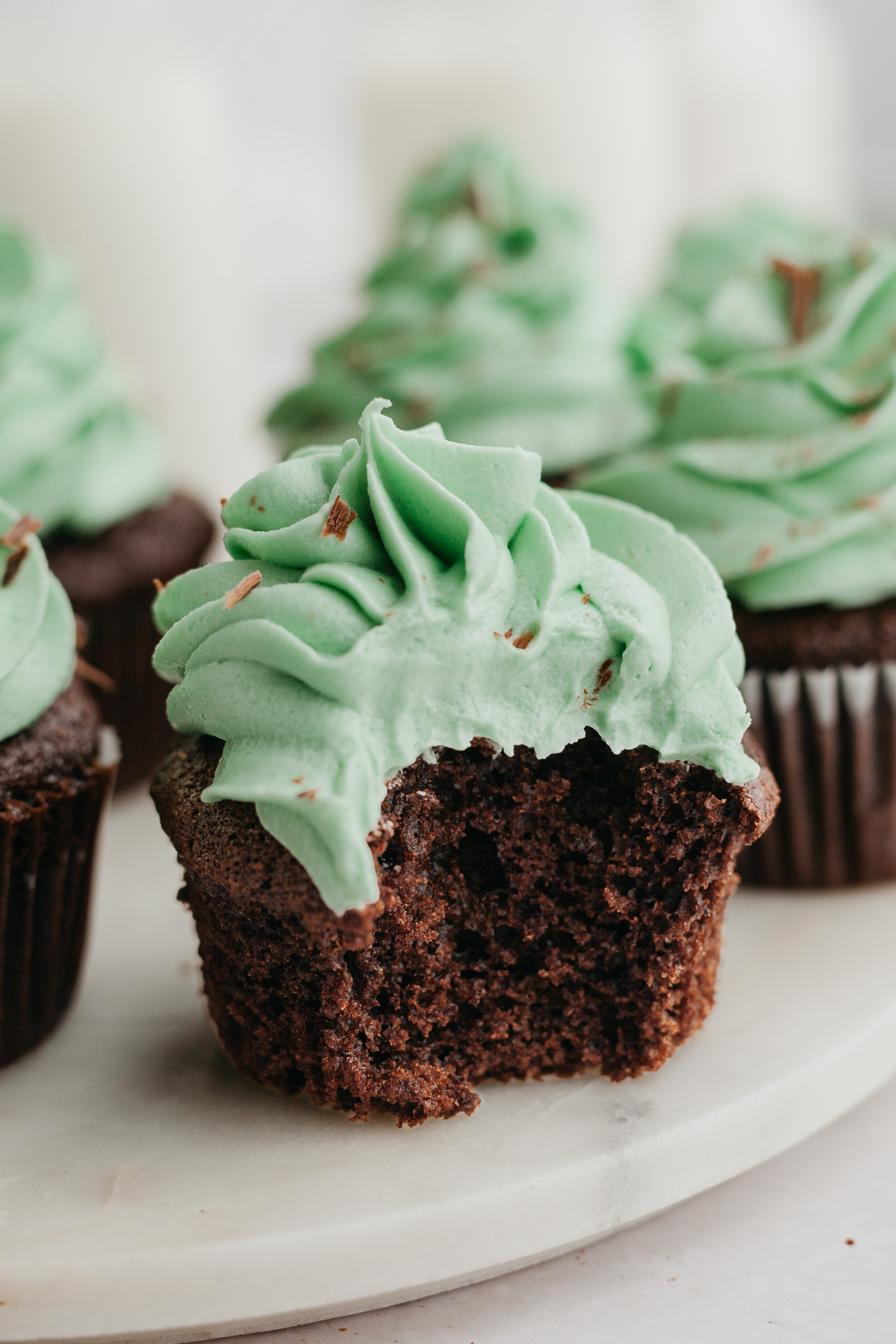 A close up of a chocolate cupcake with green frosting, a bite has been taken out of the cupcake.