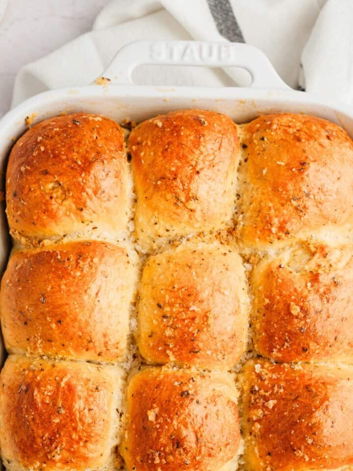Baked garlic dinner rolls in a white baking dish.