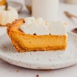 A slice of pumpkin pie topped with whipped cream.