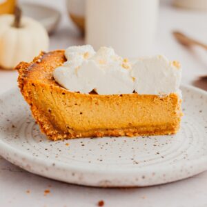 A slice of pumpkin pie topped with whipped cream.