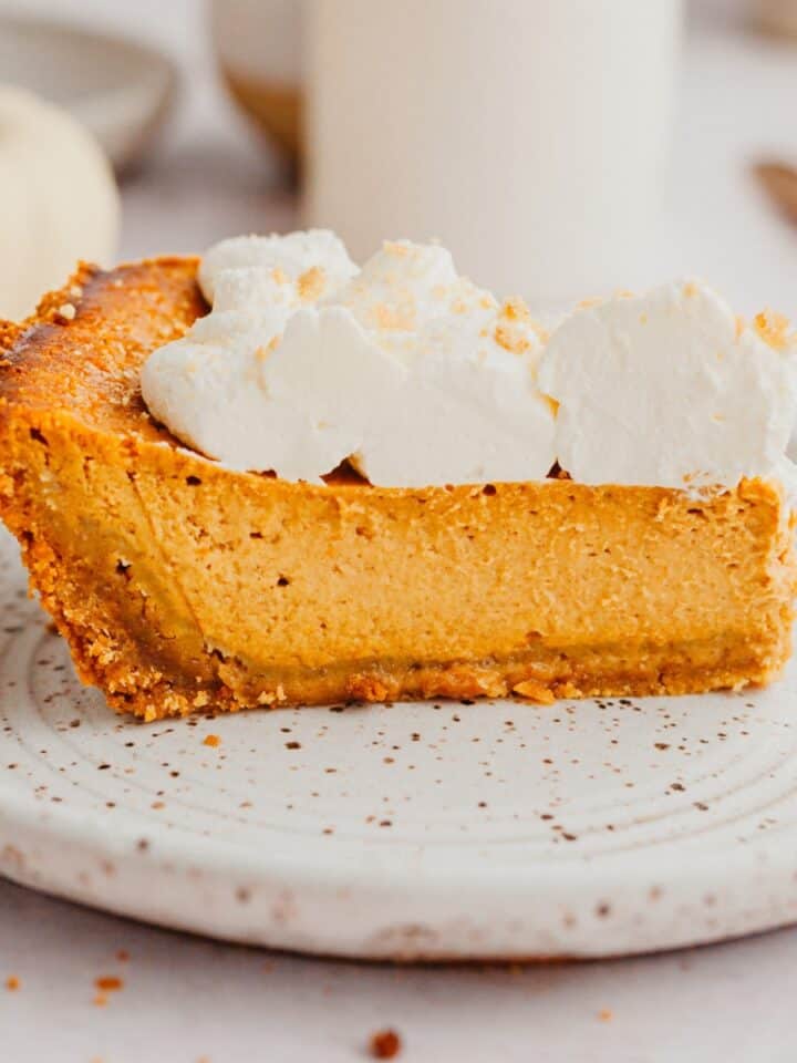 A slice of pumpkin pie topped with whipped cream.