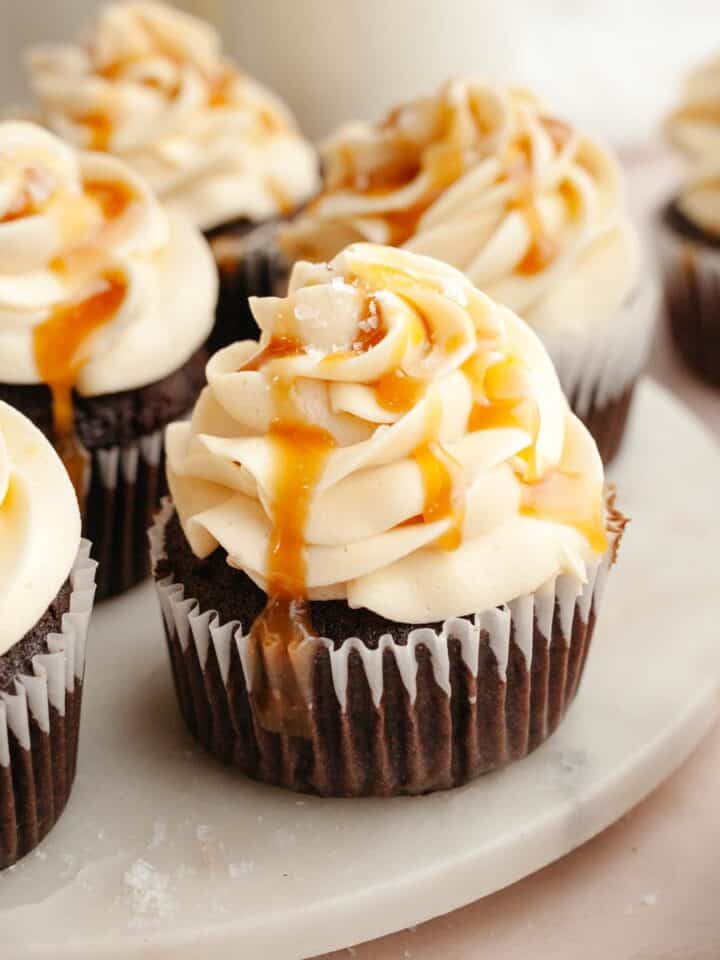 Chocolate cupcakes with caramel buttercream on white marble.