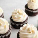 Cream cheese frosting piped onto chocolate cupcakes.