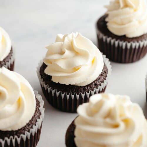 Cream cheese frosting piped onto chocolate cupcakes.