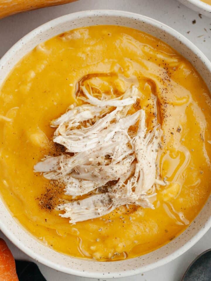 A white bowl with butternut squash chicken soup.