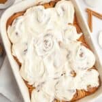 Brown butter cinnamon rolls covered with brown butter frosting in a white dish.