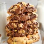 A stack of five peanut butter Nutella cookies, tour of the cookies are broken in half showing that they're stuffed with Nutella.
