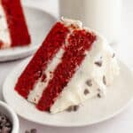 A slice of red velvet cake with chocolate chips and cream cheese frosting.