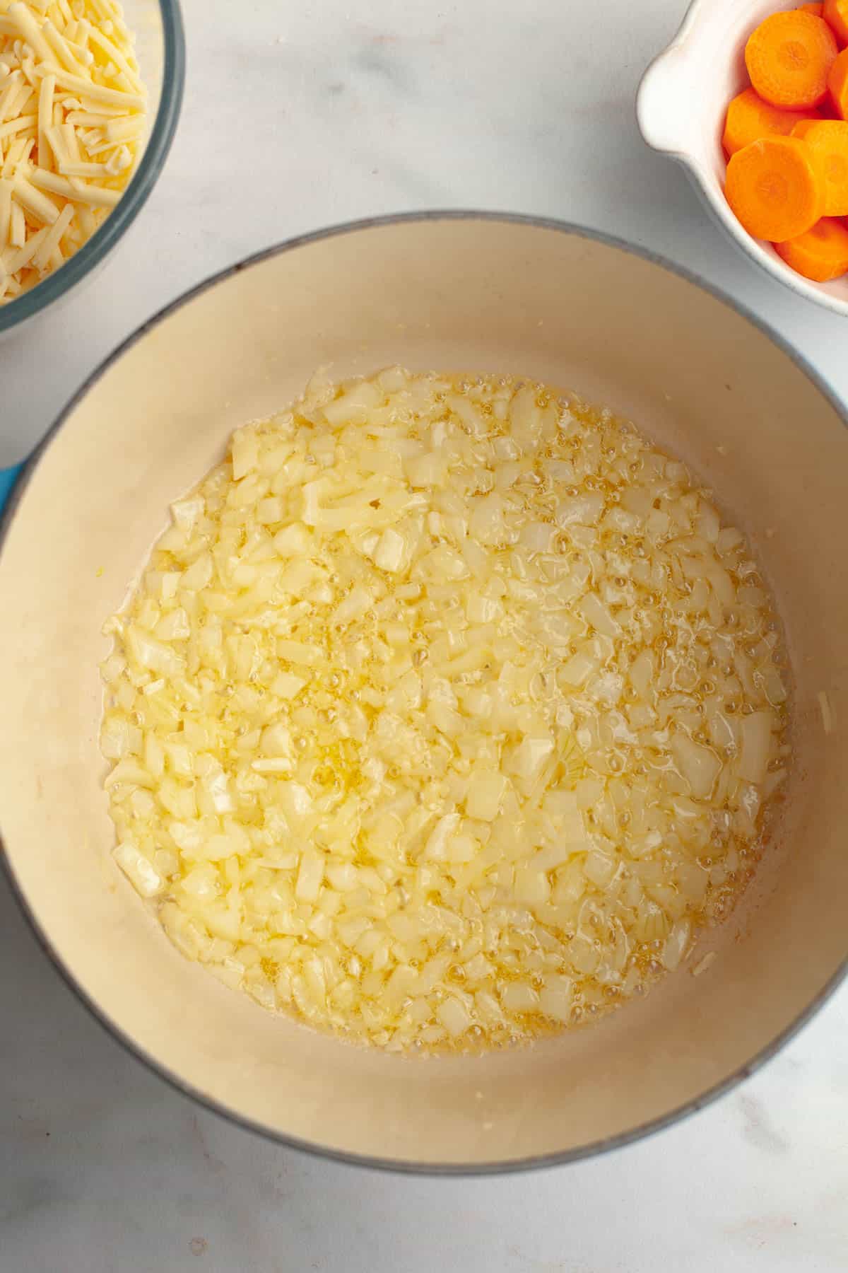 A large stockpot with melted butter and diced onions.