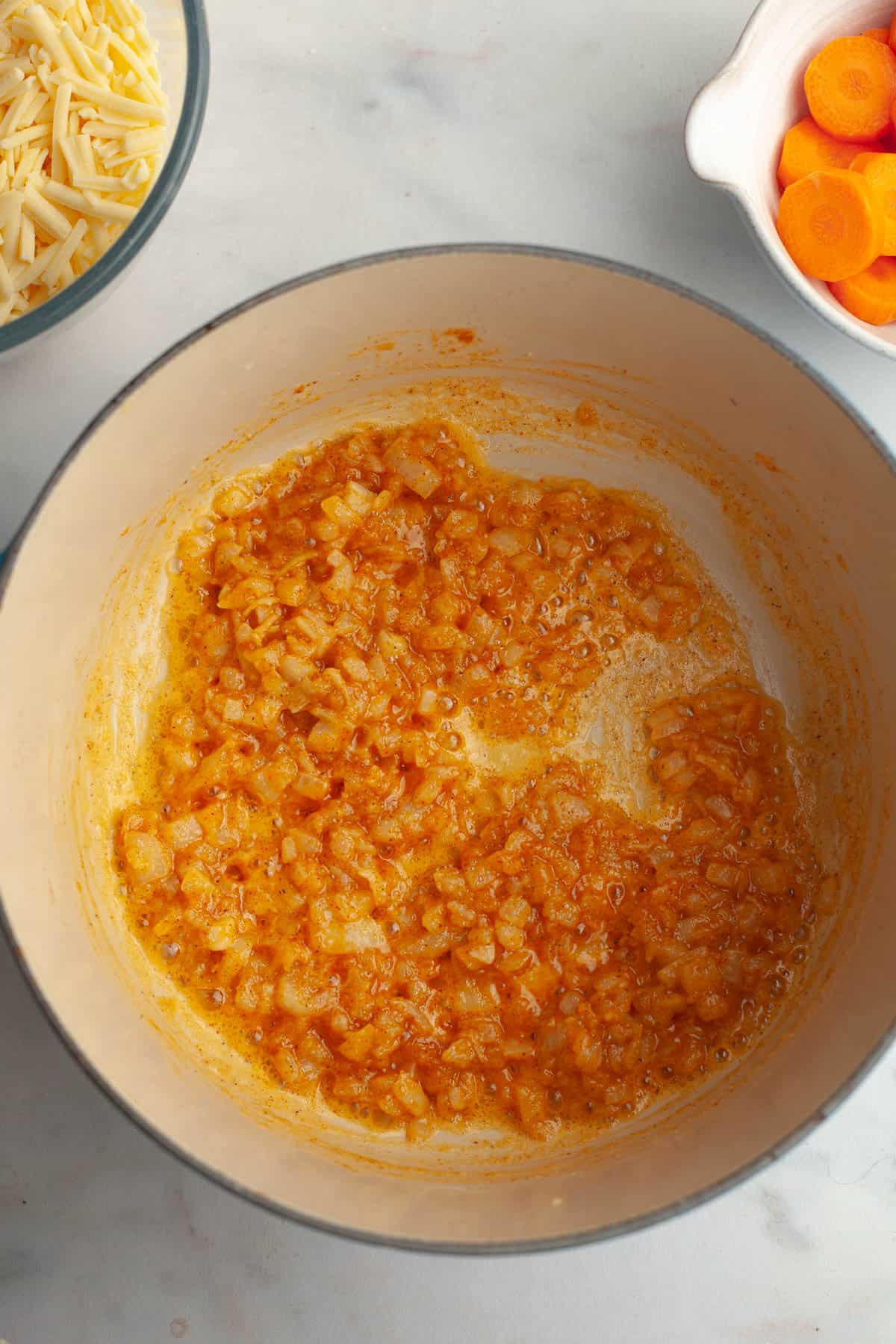 A large stock pot with melted butter, diced onions, and spices.