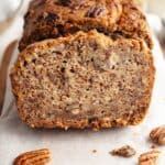A close up of a slice of pecan banana bread on parchment paper.