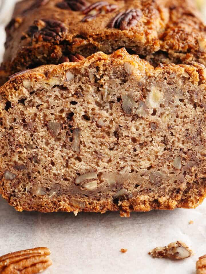 A close up of a slice of pecan banana bread on parchment paper.