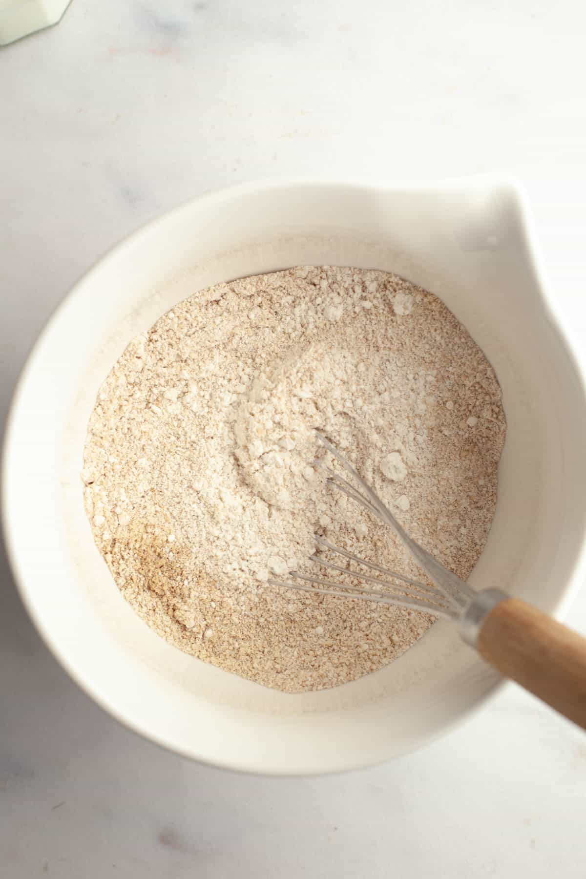 A large white bowl with whisked flour, almond flour, and cardamom.