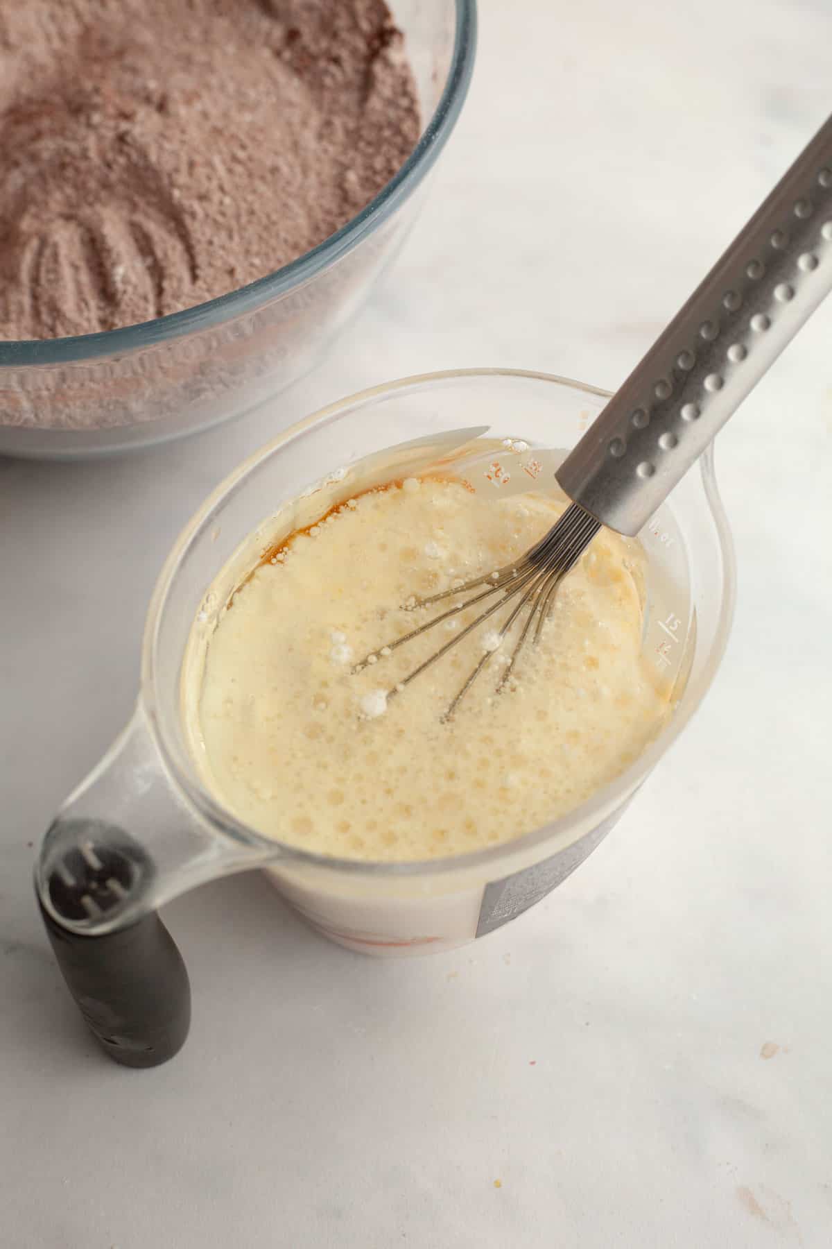 A jug with a whisk and buttermilk and oil.