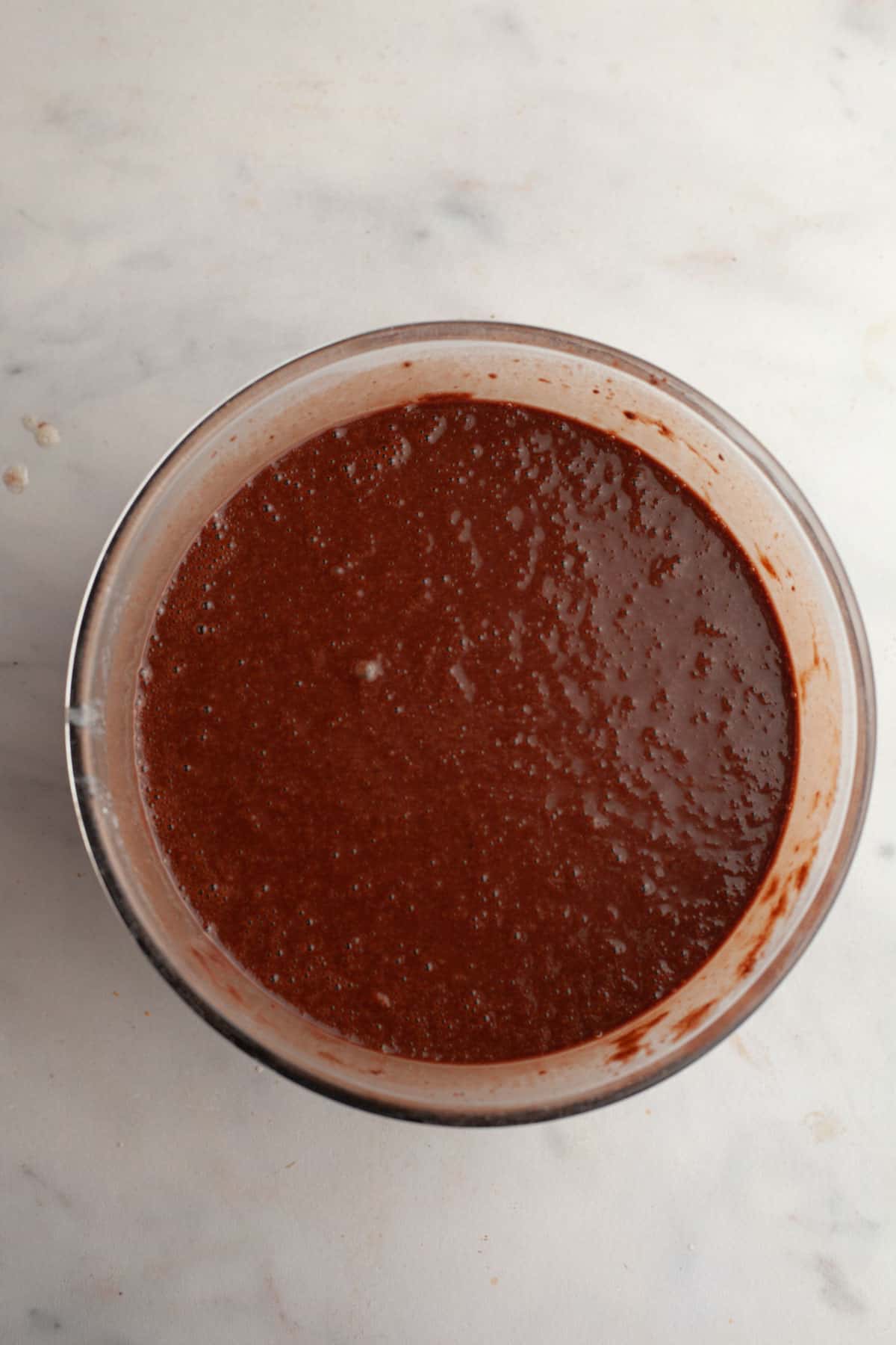 Chocolate cake batter in a glass bowl.