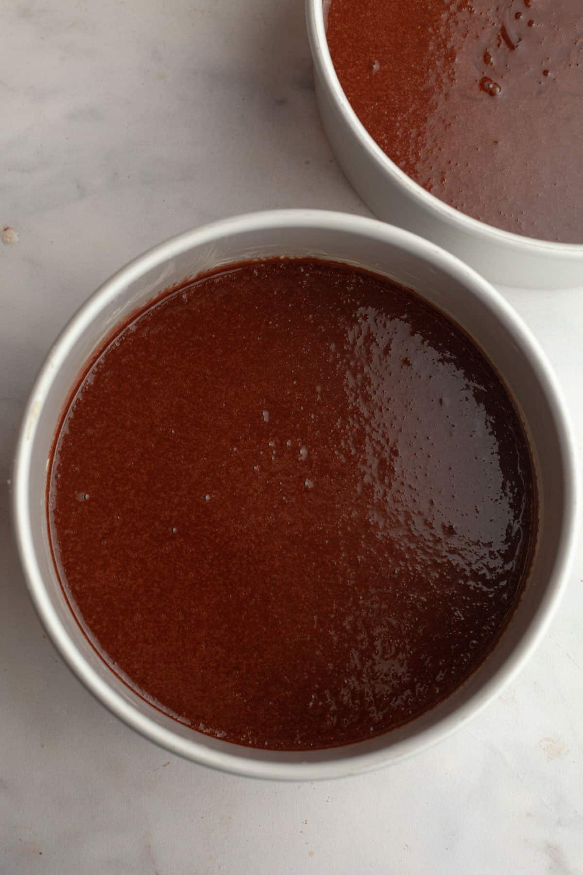 Unbaked chocolate cake in round cake pans.
