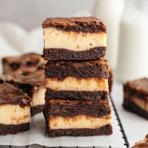A stack of three peanut butter cheesecake brownies on parchment paper.