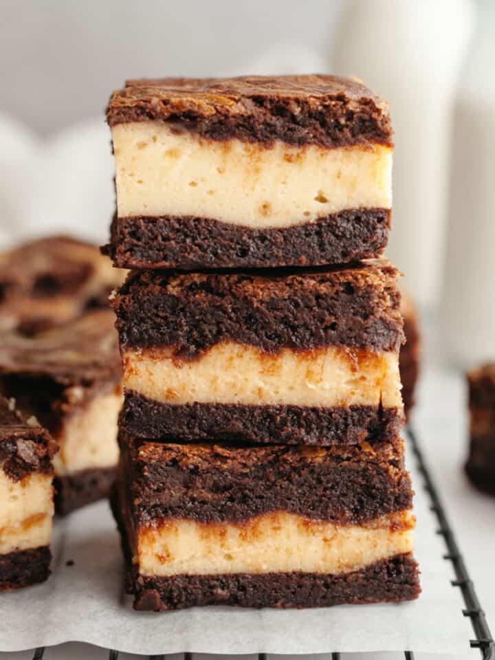 A stack of three peanut butter cheesecake brownies on parchment paper.