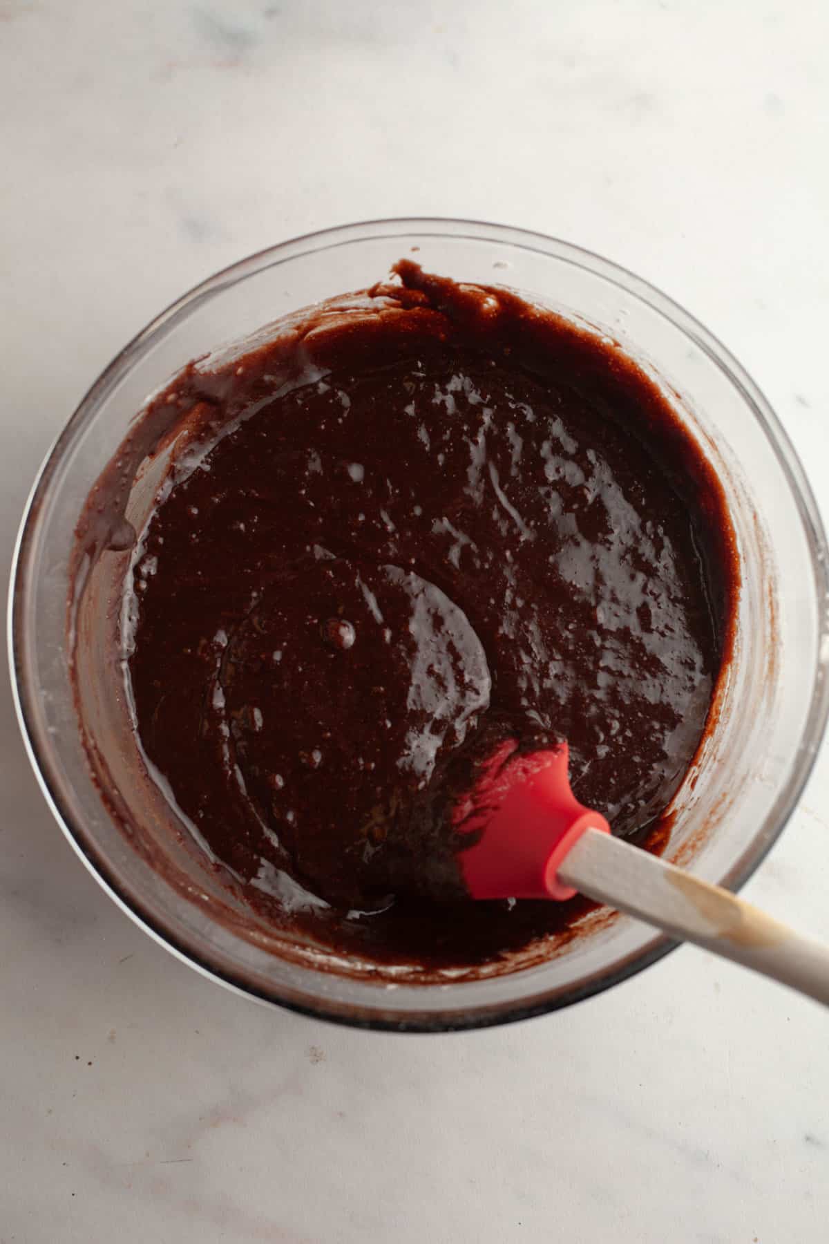A glass bowl with brownie batter in it.