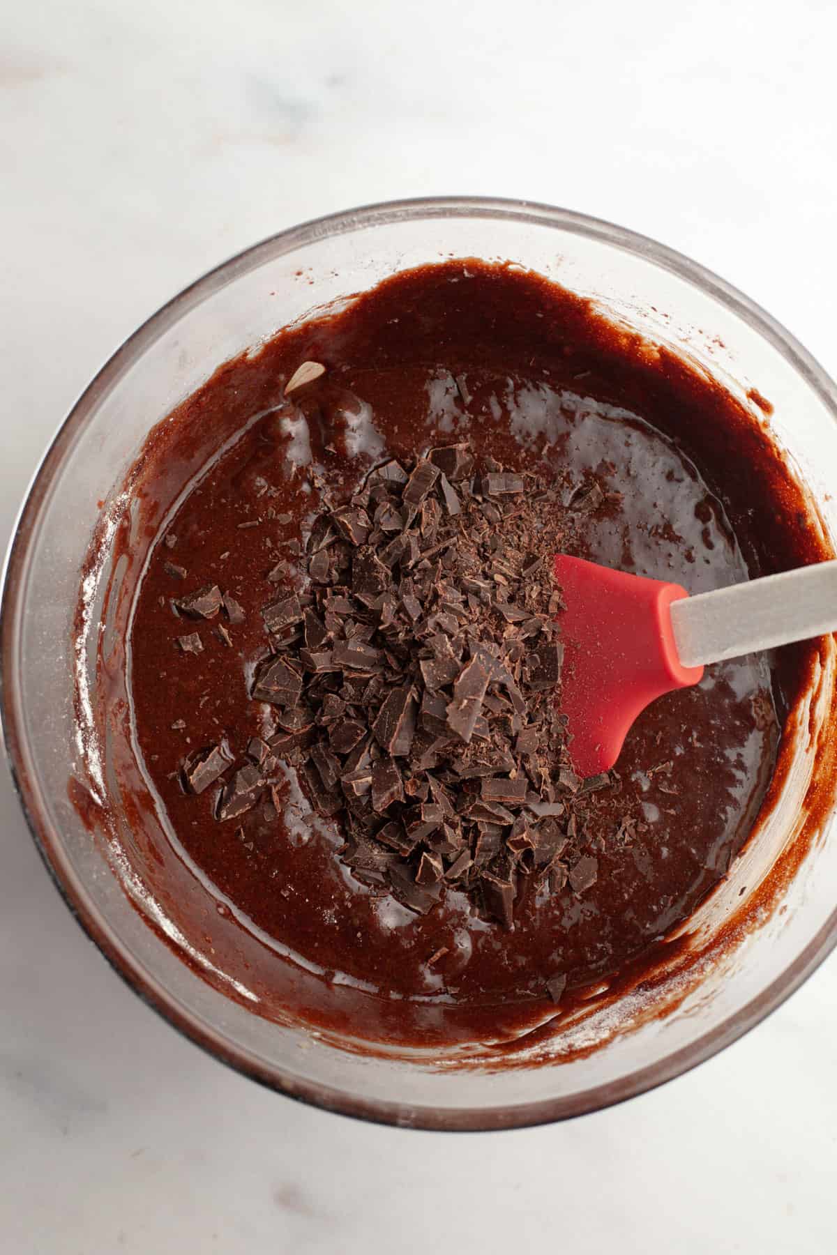 Brownie batter with chopped chocolate in a glass bowl.