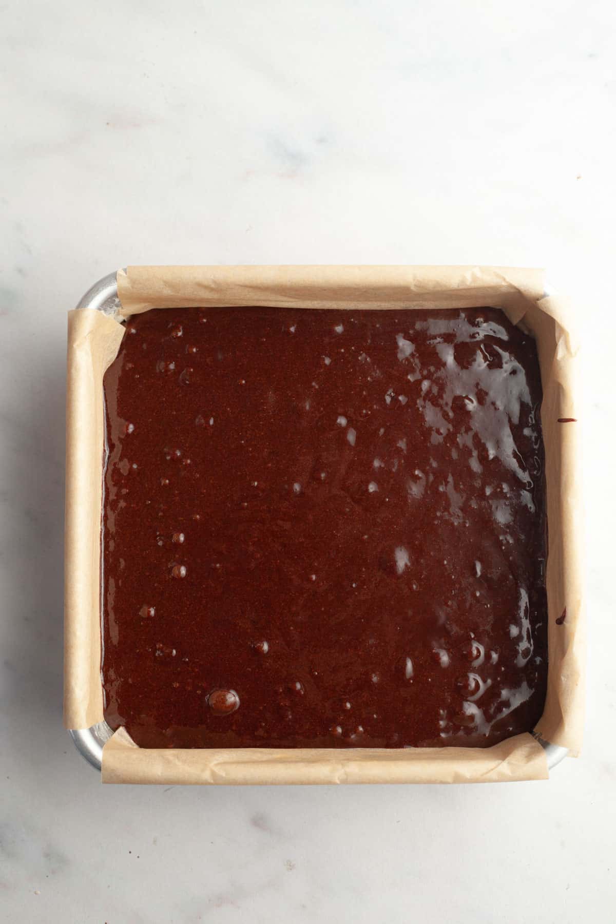 Unbaked brownies in a square pan.